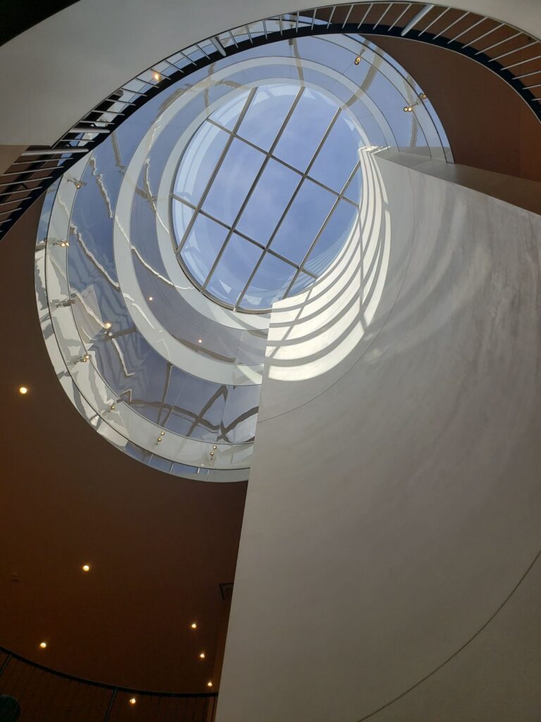 Image looking up the center of Smith College's Neilson Library to the skylight that is surrounded by spiral stairs.